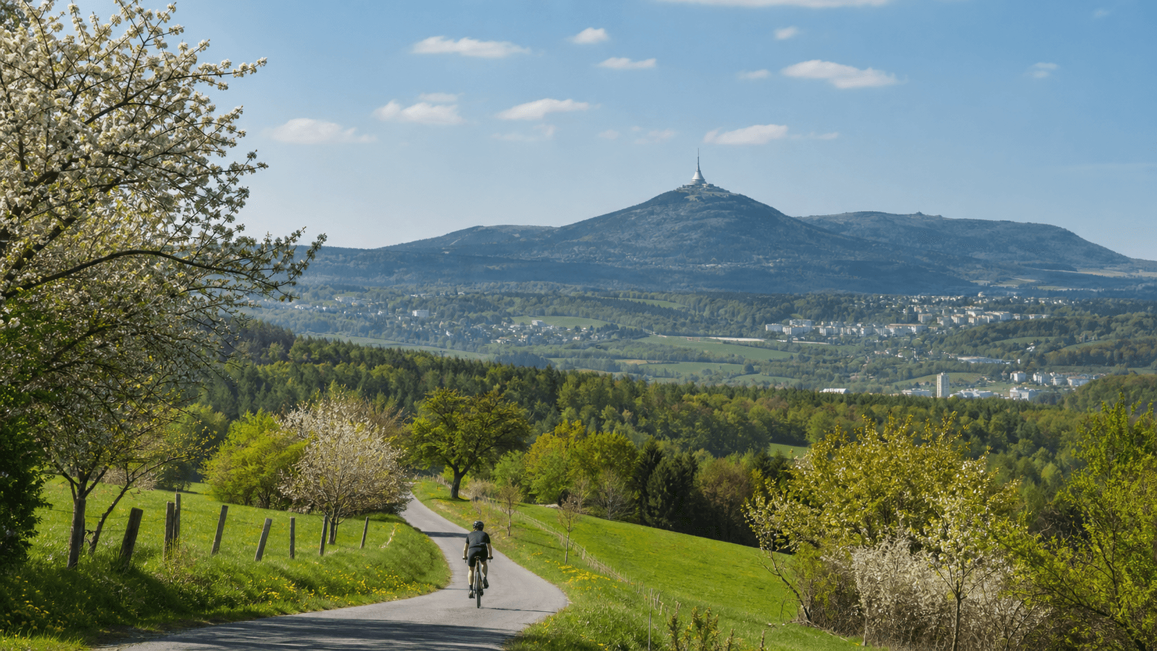 Cyklista na cestě s výhledem na Ještěd a Jizerské hory